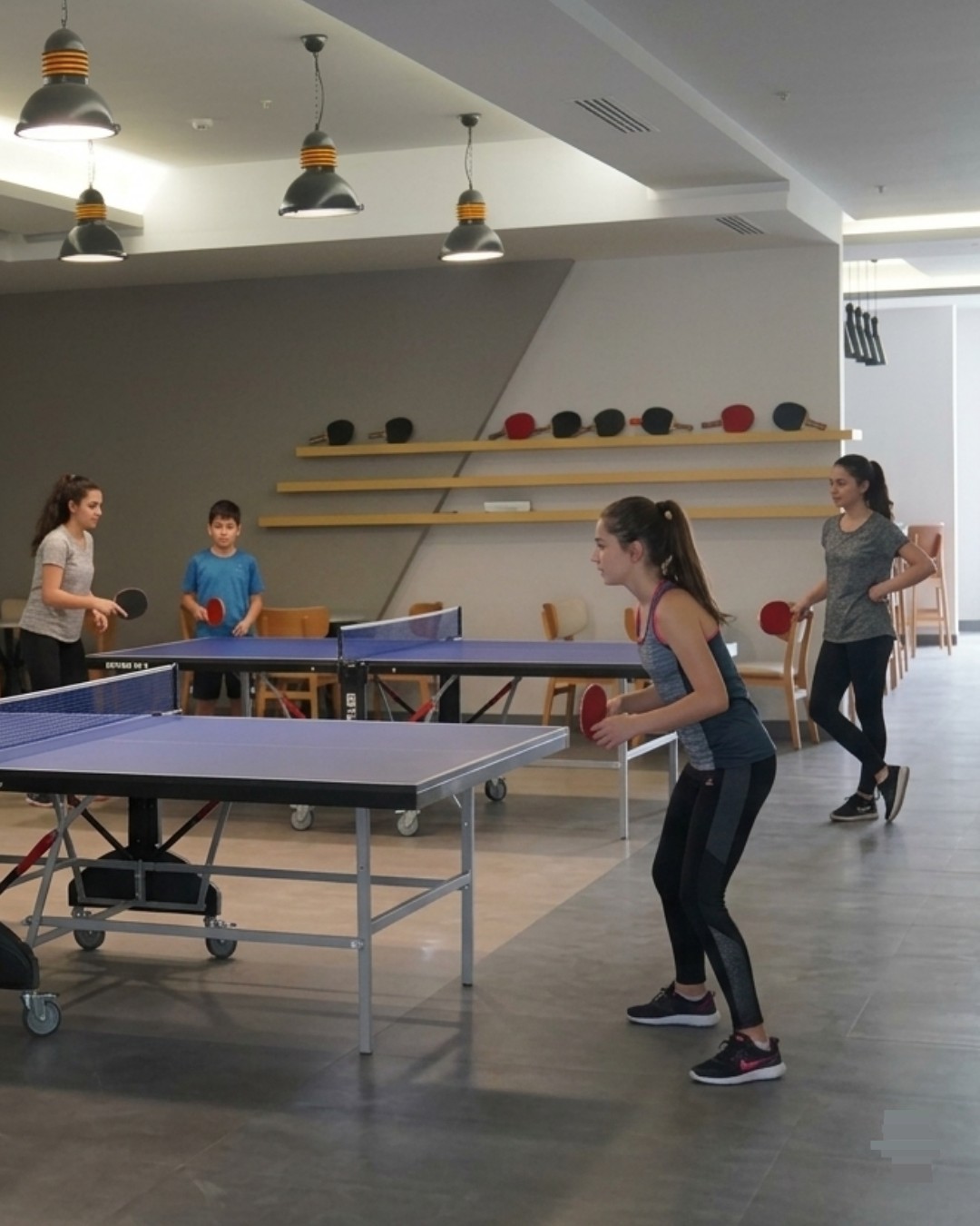 Amigos jugando tenis de mesa y billar en una sala de juegos